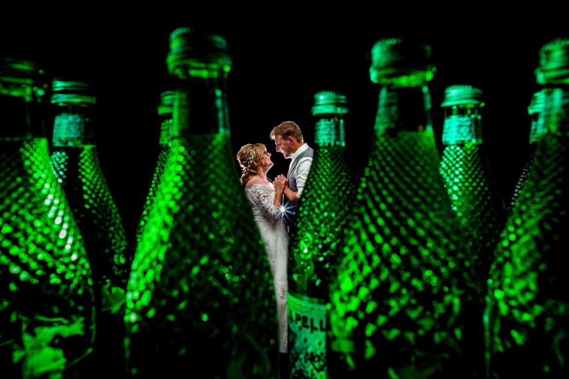 Creatieve flitsfoto tijdens de trouwreportage tussen de flessen bruiswater