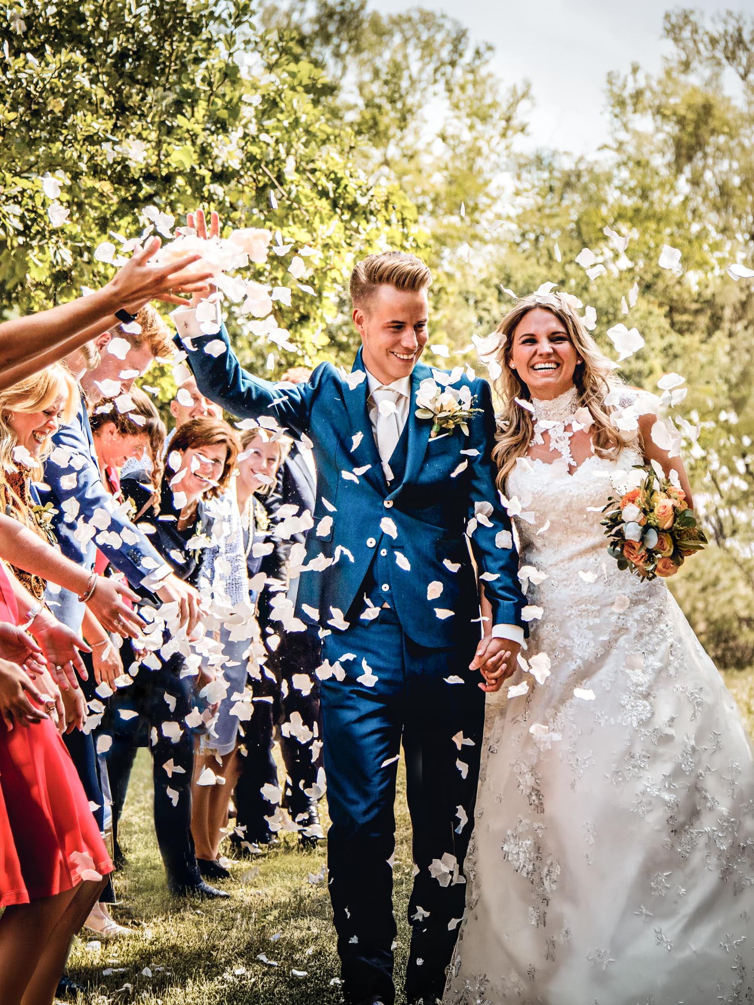 Bruidspaar geniet van een feestelijke confetti exit vastgelegd met trouwfotografie en trouwvideo door Trouwdag in Beeld. Jullie liefdesverhaal, vastgelegd in échte momenten met een mooie trouwreportage en trouwclip.